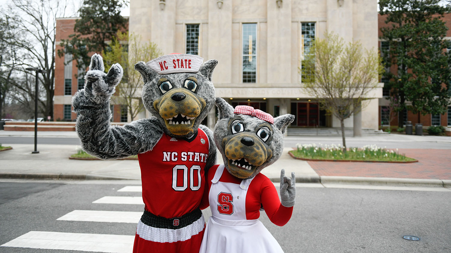 Mr. and Ms. Wuf show their school spirit in front of NC State's Reynolds Coliseum.
