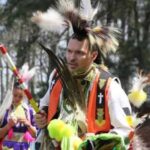 A man of American Indian descent, dressed in traditional garb, participates in an NC State Native American Alumni Network ceremony.