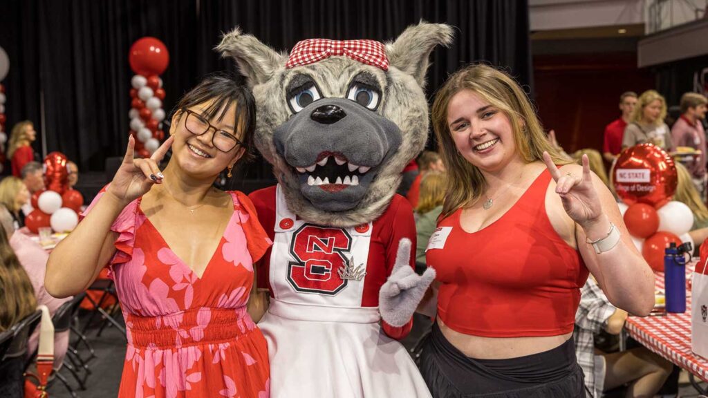 Incoming NC State students show the Wolfies hand sign alongside Ms. Wuf at the 2024 Legacy Luncheon.